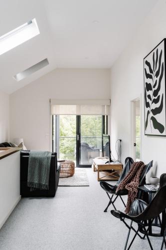 a white living room with chairs and a couch at Athlete's Retreat - 21A Service Street in Porepunkah