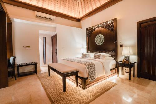 a bedroom with a large bed and a table at Ramayana Suites and Resort in Kuta