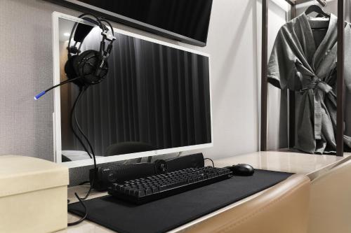 a desk with a computer monitor and a keyboard and headphones at HOUND HOTEL Incheon Airport in Incheon