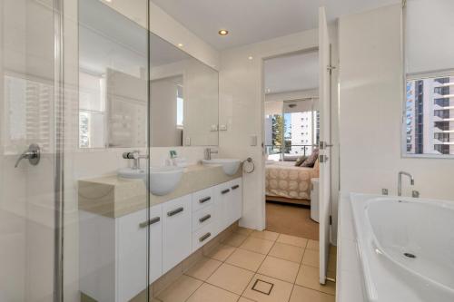Un baño con dos lavabos, una bañera y una ducha. en Eden Apartments Unit 401, en Gold Coast