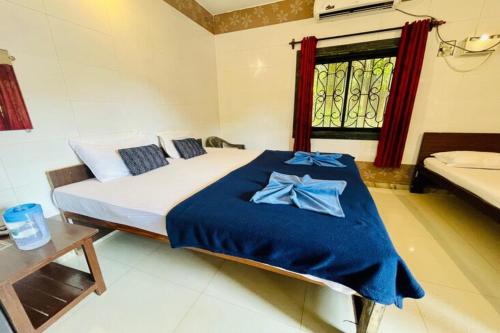 a bedroom with a bed with blue sheets and a window at Beach Queen By The Sea in Calangute