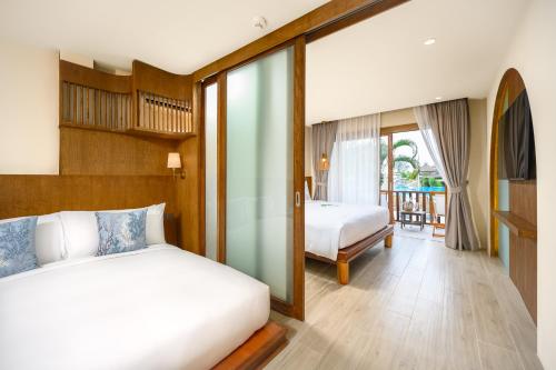 a bedroom with two beds and a balcony at Arinara Beach Resort Phuket - SHA Extra Plus in Bang Tao Beach