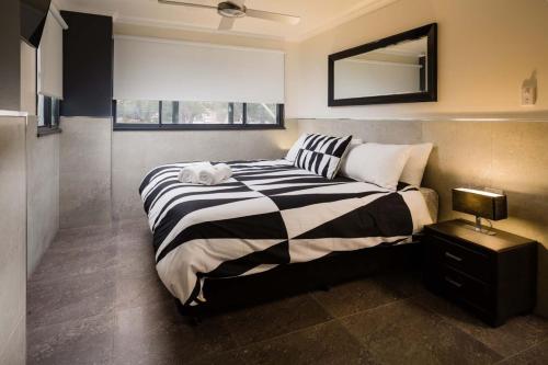 a bedroom with a bed with a black and white blanket at Nautilos On The Harbour in Newcastle