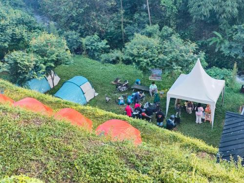 a group of people sitting in a field next to tents at D'Sentra Camping Ground in Pengalengan