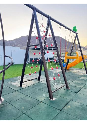 a swing set in a park with a playground at 1 - BLUE WORLD - Al Dana Villas in Fujairah