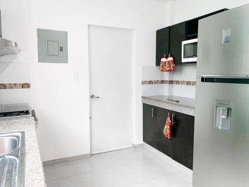 a white kitchen with a refrigerator and a sink at Casa de 3 dormitorios, piscina privada, parqueo free in Estancia Vieja