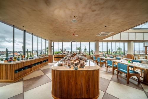 a restaurant with tables and chairs and large windows at TUI BLUE Berawa Hotel and Villas in Canggu