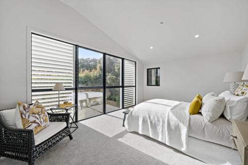 Un dormitorio blanco con una cama y una silla. en Brand new Luxury home in Remuera, en Auckland