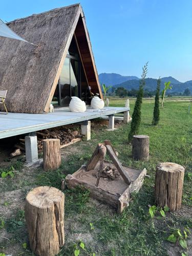 a house with a thatched roof and some logs at เฮือนจินดา Jins BANN A2 in Ban Wang Masiu