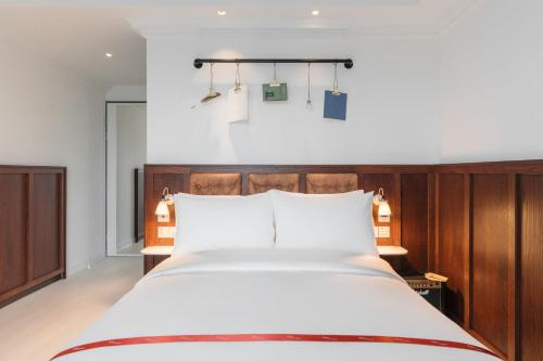 a bedroom with a large white bed with wooden headboard at Ruby Stella Hotel London in London