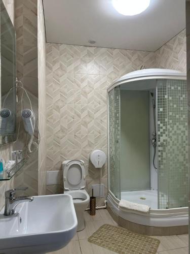 a bathroom with a sink and a toilet and a tub at Deluxe SPA-Hotel in Ustʼ-Kamenogorsk