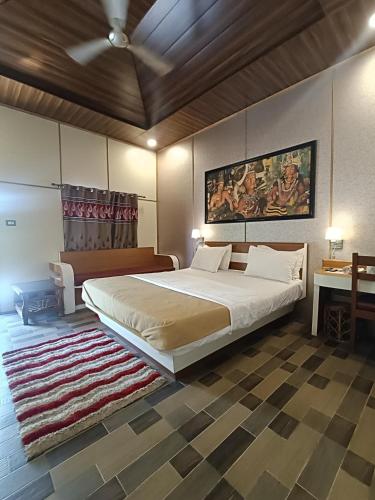 a bedroom with a large bed with a painting on the wall at Ellora Heritage Resort in Ellora