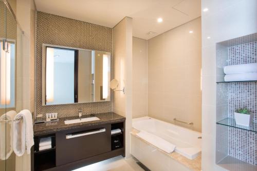 a bathroom with a sink and a tub and a mirror at I Square Hotel in Gimhae