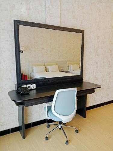a desk with a mirror and a chair in a room at Grand Cahaya Hotel Pangandaran in Pangandaran