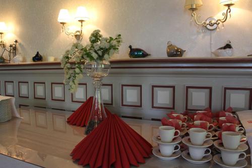 a table with cups and a vase with red napkins at Woikoski Feeling - Kirjokiven Kartano in Joutsenlahti