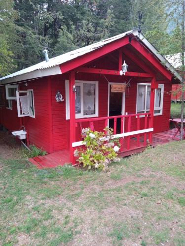 a red cabin with a red porch and a door at Cabaña Mawinda in Pucón