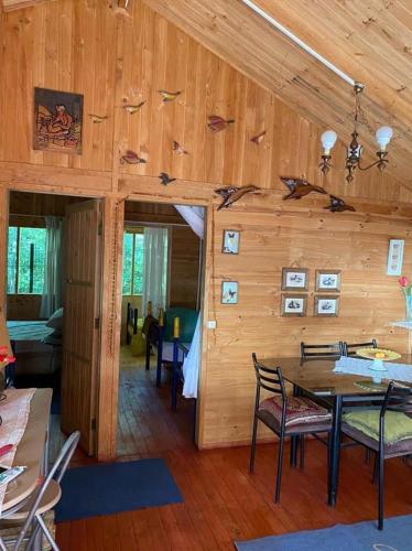 a room with a wooden wall with a table and chairs at Cabaña Mawinda in Pucón