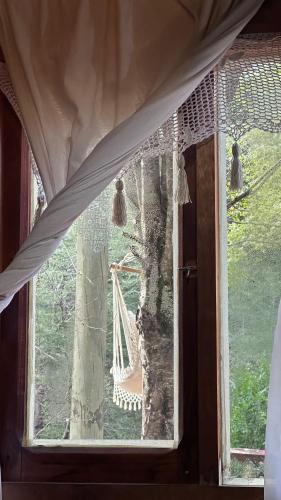 a window with a hammock in a tree at Cabaña Mawinda in Pucón