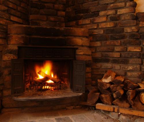 a brick fireplace with a fire in it at Matsunoki-tei in Otari