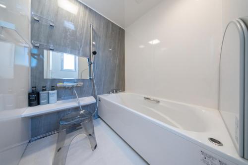 a bathroom with a tub and a chair next to a sink at クリスタルヴィラ南城 in Azama