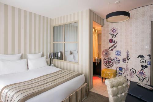 a bedroom with a bed and a chair and a window at Hôtel Le Bellechasse Saint-Germain in Paris