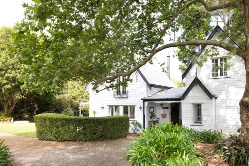 a white house with a tree in front of it at Exclusive Luxury Designer Cottage Estate for 10 - Peaceful Retreat Just 8 Minutes from Maleny in Witta