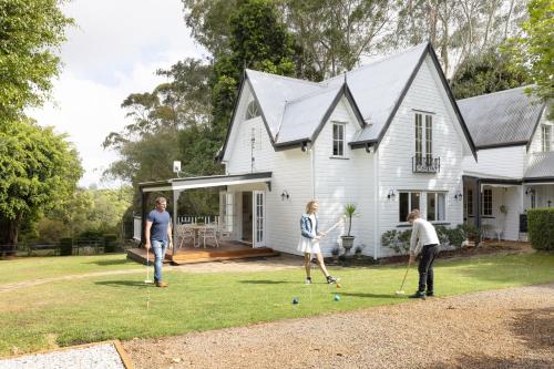 a group of people playing a game of golf in front of a house at Exclusive Luxury Designer Cottage Estate for 10 - Peaceful Retreat Just 8 Minutes from Maleny in Witta