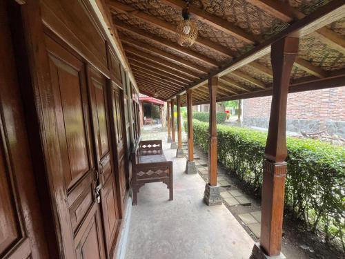 a porch with a bench under a wooden roof at Saka Homestay Boutique & Cafe in Borobudur