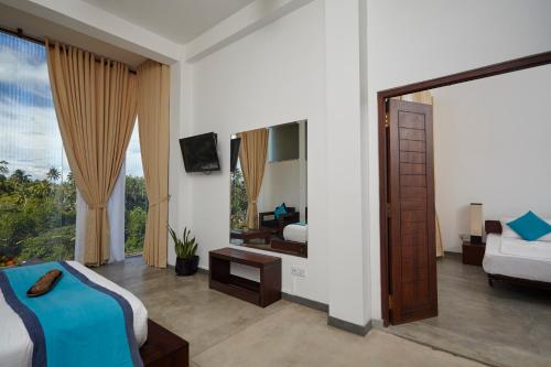 a bedroom with a bed and a tv and a mirror at Garton's Cape in Ahangama