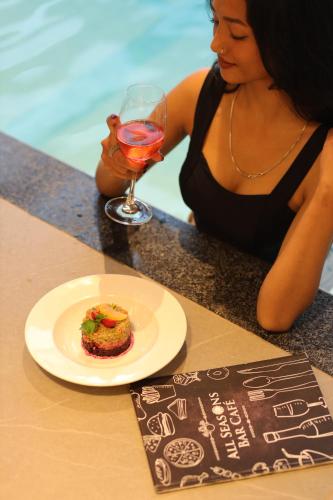 a woman sitting at a table with a plate of food and a wine glass at The Oasis Mussoorie - A Member of Radisson Individuals in Mussoorie