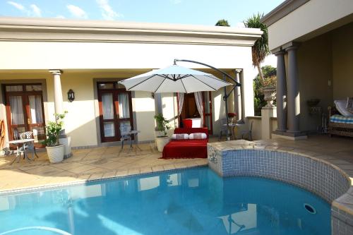 a swimming pool with an umbrella next to a house at Villa Lugano Guesthouse in Johannesburg