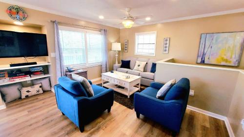 a living room with two blue chairs and a tv at Beachside Home, Heated Pool, Steps 2 beach, Meticulous, 5-star Rated in Coquina Gables
