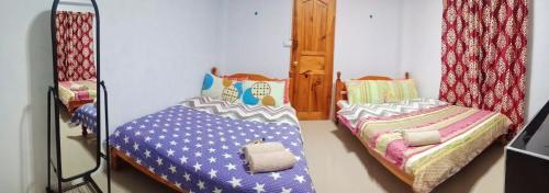 two twin beds in a room with a mirror at SOLEIL de SAGADA INN in Sagada