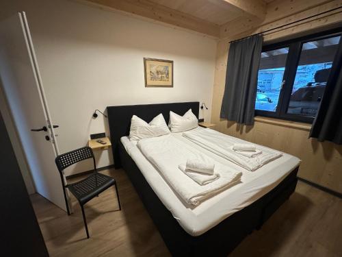 a bedroom with a bed with a chair and a window at Chalet-Style Apartment Sonnleitn Nassfeld in Hermagor