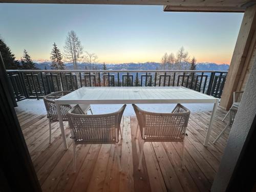 a white table and chairs on a deck with a view at Chalet-Style Apartment Sonnleitn Nassfeld in Hermagor