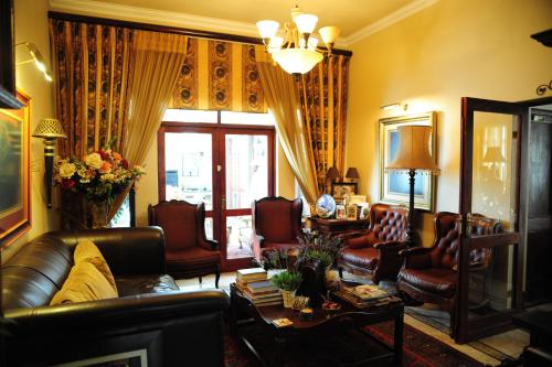 a living room with a leather couch and chairs at Villa Lugano Guesthouse in Johannesburg