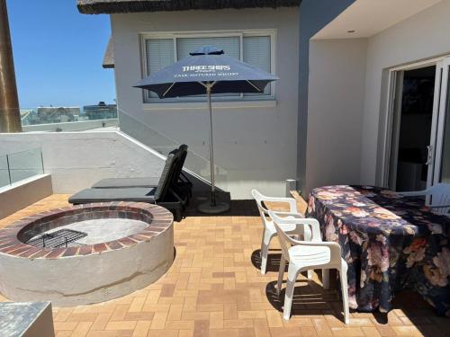 a patio with an umbrella and a table and chairs at Jongensfontein Beachside Villa in Jongensfontein