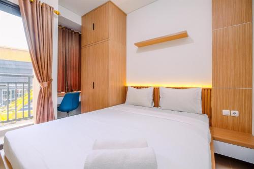 a bedroom with a white bed and a window at Simply and Nice Studio at Transpark Cibubur Apartment By Travelio in Depok