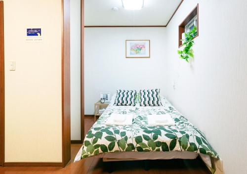 a bedroom with a bed with a green and white comforter at Shalom 鶴橋 市中心地铁口徒步10秒可到民宿 地铁6分钟直达难波 大阪3条地铁交汇处 30分钟直达奈良 in Osaka