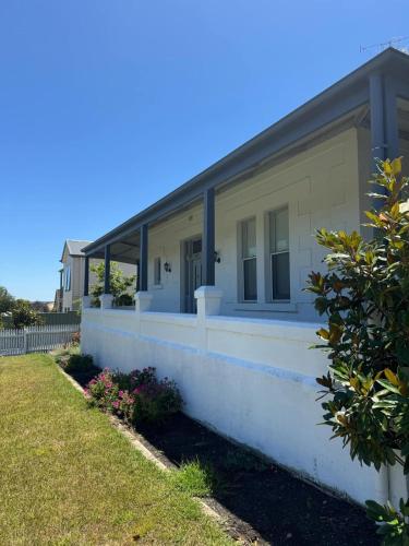 a white house with a fence and a yard at 1920's Local Heritage Character home 'Rangatira' 3 bedroom, 2 living room family home in Mount Gambier