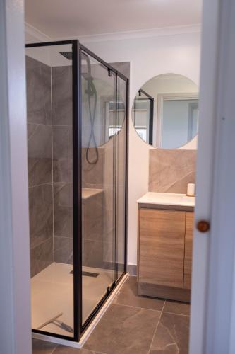 a glass shower in a bathroom with a sink at Baudins Accommodation in Naracoopa