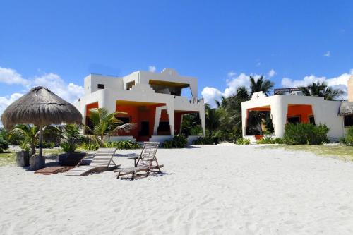 una casa en la playa con sillas y sombrilla en Mayan Beach Garden en El Placer