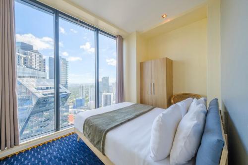 マニラにあるStayHere 3BR Penthouse Knightsbridge Makatiのベッドと大きな窓のある寝室