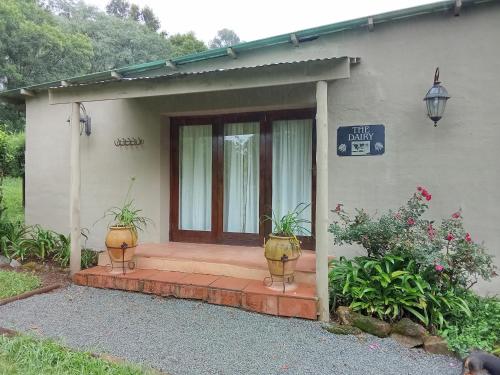 a house with two potted plants in front of a door at The Retreat Country Lodge in Romelcoh
