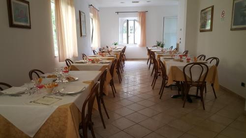 a row of tables in a room with white tables and chairs at Hotel Elisabetta in Cinquale