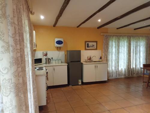 a kitchen with white cabinets and a black refrigerator at The Retreat Country Lodge in Romelcoh