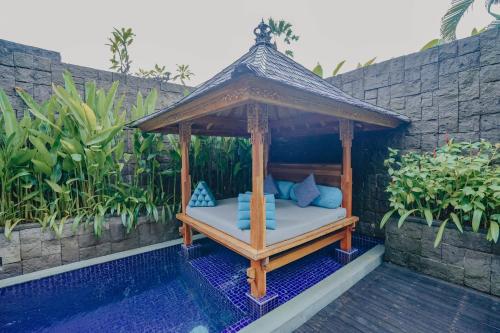 a gazebo sitting next to a swimming pool at Maca Villas & Spa Bali in Seminyak