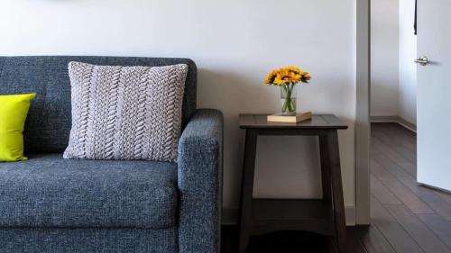 a blue couch with a vase of flowers on a table at 16th and 18th FL Bold CozySuites with pool gym in Dallas