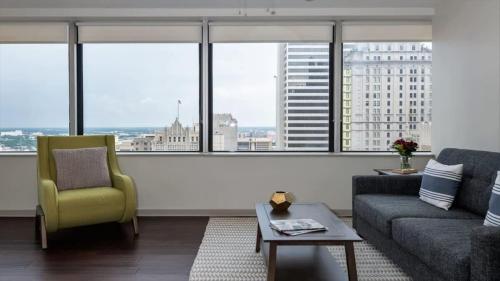 a living room with a couch and a chair and windows at 16th and 18th FL Bold CozySuites with pool gym in Dallas