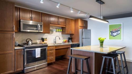 a kitchen with wooden cabinets and stainless steel appliances at 16th and 18th FL Bold CozySuites with pool gym in Dallas